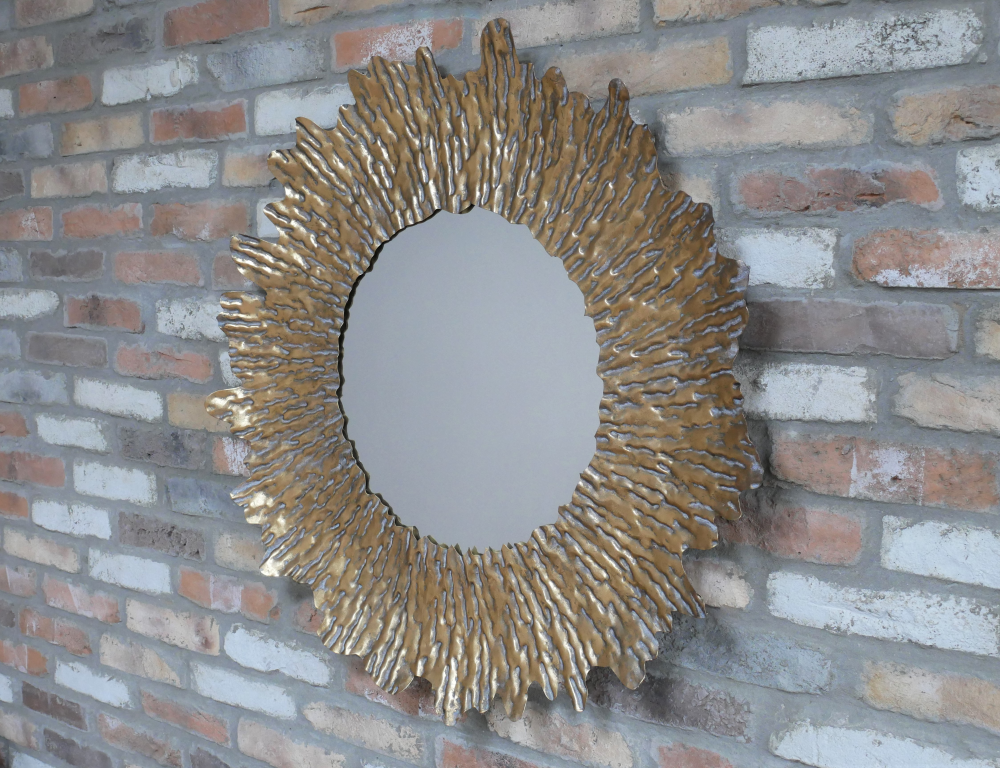 Miroir mural rond représentant un soleil. Ce miroir légèrement incurvé est entièrement en métal et joliment travailler avec une finition vieillie et dorée, pour un bel aspect de rayons de soleil.
