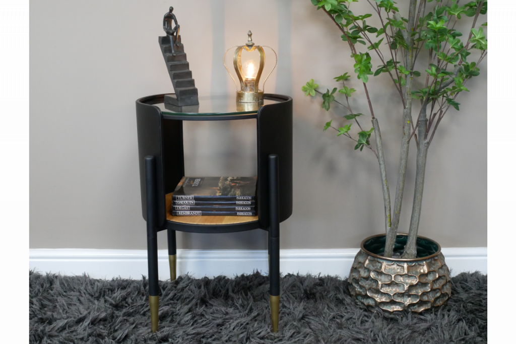 Petite table ronde avec deux plateaux. Le meuble est en métal, finition noire avec un plateau en verre et un plateau en bois. Joli bout de canapé original avec un design moderne qui peut aussi être utilisé comme chevet.